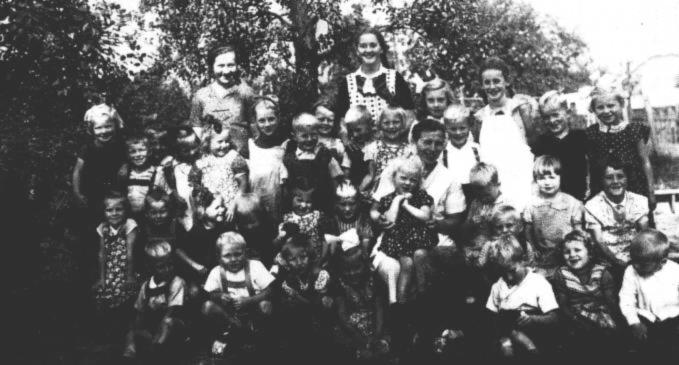 Den Westrhauderfehner Kindergarten leitete Tante Agnes, die nicht von hier war. Ihr zur Seite standen Meta Leefoge und Dita Oltmanns, die auf unserer Aufnahme aus dem Jahre 1939 im Hintergrund zu sehen sind. Annegret Stockmar, die in der oberen Reihe ganz rechts steht, konnte uns noch etliche Namen nennen. Links neben ihr steht Alfred Ohling, dann Herta und Uwe Schmidt. ber Tante Agnes steht Frieda Kretzmer, aber das Mdchen neben ihr ist unbekannt. Dann folgen die Zwillinge Karl-Heinz und Gerald Gewald. Zwischen ihnen steht dahinter Mathilde Ulpts. Das groe Mdchen mit der weien Schrze ist Martha Thomsen, und die schne Schleife ist auf dem Kopf von Anneliese Kramer befestigt. Dahinter stehen erneut Zwillinge, nmlich Rudolfine und Johanne Rosenboom. Neben ihnen ist Helmut Detmers zu erkennen, und das Mdchen ganz links wollte sich nicht zu erkennen geben. Darunter in der zweiten Reihe hockt wieder ein unbekanntes Mdchen. Dann folgen Anton Hesenius, Hildegard Detmers, die zur Seite schaut, und Karin Bernhards sowie Hilde Kramer. Die nchsten drei Kinder wollten ihren Namen nicht nennen. Die vorletzte knnte eine Bodamer sein, und das Mdchen ganz rechts ist Elfriede Jelden. Unter ihr sitzt unten ganz rechts Theo Rosenboom. Die nchsten drei Kinder sind wieder unerkannt. In der Mitte mit der schnen weien Schleife sitzt Erna Hesenius, daneben unbekannt, dann Heinz Kretzmer und ein Noormann? -