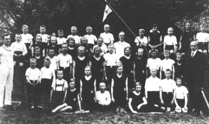 Die Jugendturnabteilung vom TV Holterfehn etwa um 1930. Da hatte Ostrhauderfehn noch gar keinen Sportverein! Andreas de Freese hat uns geholfen, die Namen herauszufinden. Links steht Ubbo de Freese als Vorturner, auf dem Barren sitzt Andreas Oldermann, dahinter Rudolf de Buhr, Hinrich Heselmeyer, Andreas de Freese, Fritz Hemmen, Hermann Wulf, Hans Hinrichs, stehend Vorturner Rudolf Wulf, mit Fahne Bernhard Freesemann, dann Antine Gerdes, Hans Freesemann, Rena Ewen mit ihren tollen Zpfen und ganz rechts Gerhard Oldermann. Dann sitzen da noch vier Mdchen und ein Junge auf dem vorderen Barrenholm: Gertrud Rudat, Hanni Kramer, Agnes Neehus, Johanne Wulf und Karl Freesemann. Die dritte Reihe beginnt mit Trientje Brg, es folgt ,,Bebe" Bernhard Janssen, Oltmann Tinnemeyer, Gesine Loots (?), Therese Steenhoff, Siebo Hickmann, Luise Spieker, Gesine Janssen, Anton Peper, Heinrich Steenblock, Anni Peper und Lehrer Bertus Pfeiffer. In der vorderen Reihe stehen: Theo und Georg Renken, es kniet Gerhard Hickmann (Pastor sien Jung), Irene Hickmann, Theda Kramer, Bernhard Vietor, Rosa Klock, Mathilde Lhring, Karl Noormann, Johann Bu und Hermann Lhring.