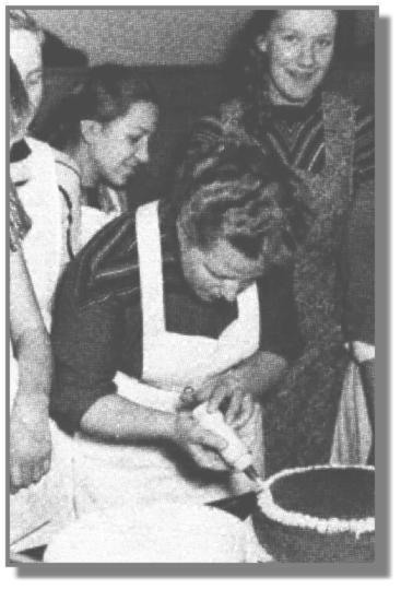 Die damalige Leiterin der EWE-Lehrkche in Leer, Frau Schobert, zeigt Anni Susan und Gisela Appeldorn, wie eine Torte fachgerecht garniert wird.